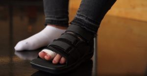 Patient wearing surgical shoe for broken toe.